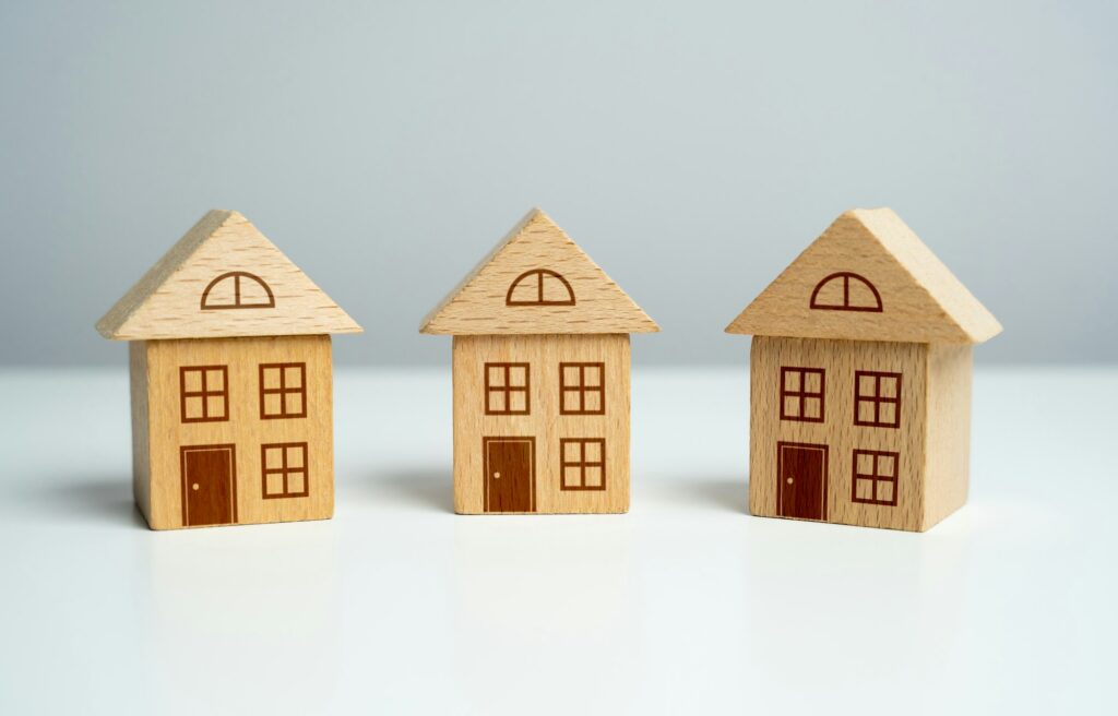 Three wooden toy houses. Offers on real estate market. Mortgage.